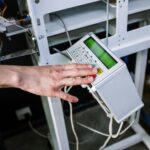 Detailed view of a person's hand operating a control panel on a coffee roasting machine.